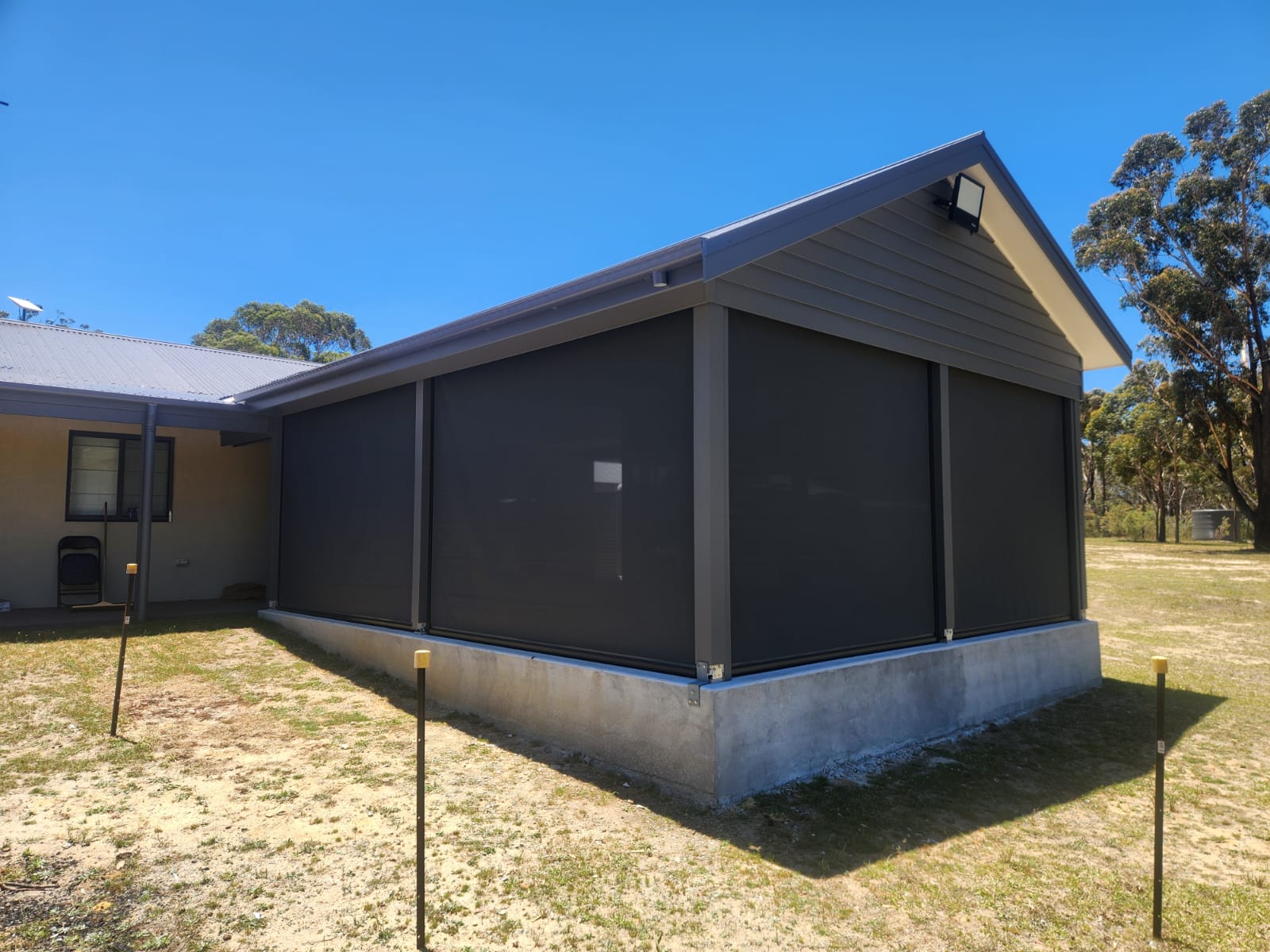 Ziptrak awnings installed around a covered alfresco area at a Wollongong home, with dark fabric panels and track-guided sides.
