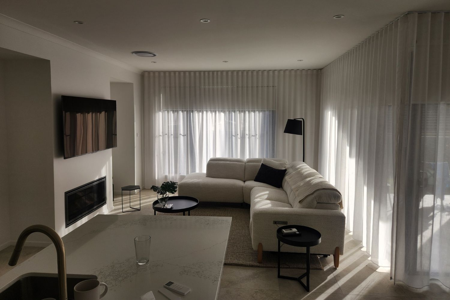 Full-height sheer curtains installed in a modern open-plan Wollongong living room by Apollo Blinds Wollongong.
