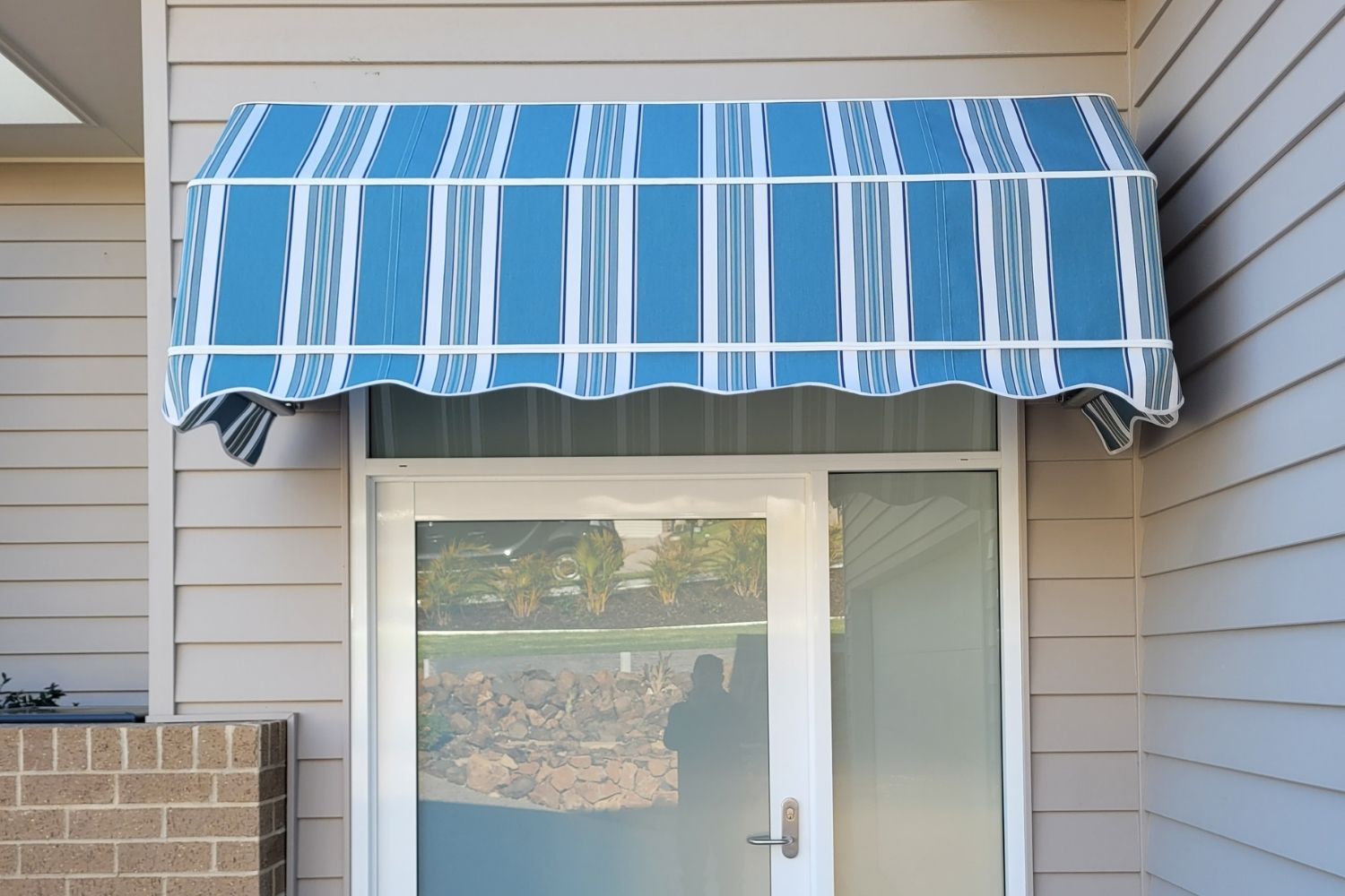Blue striped Dutch canopy awning installed above a glass entry door by Apollo Blinds Wollongong