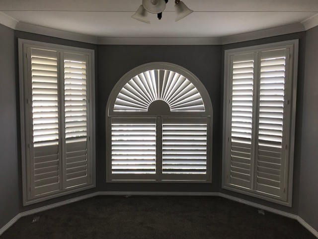 Custom shaped white shutters fitted to an arched feature window by Apollo Blinds Tamworth.